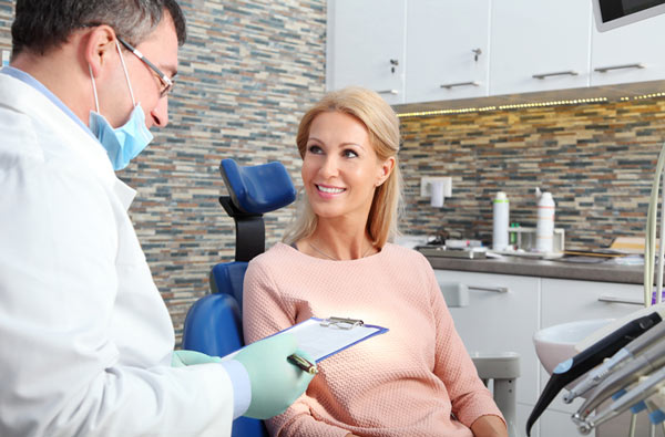 A woman talking to dentist during oral cancer screening