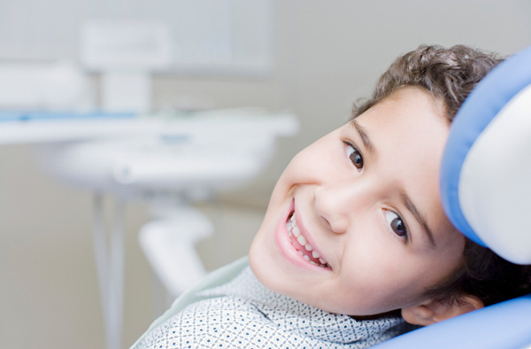 Young boy sitting on exam chair and smiling with healthy teeth