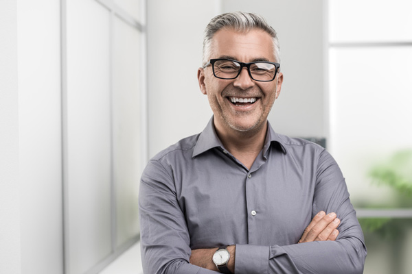 Man with glasses smiling with his arms crossed