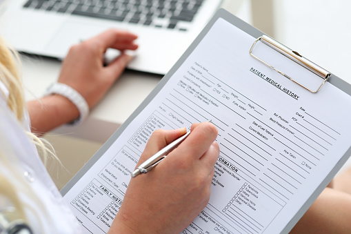 New patient forms being filled out on a clip board with pen