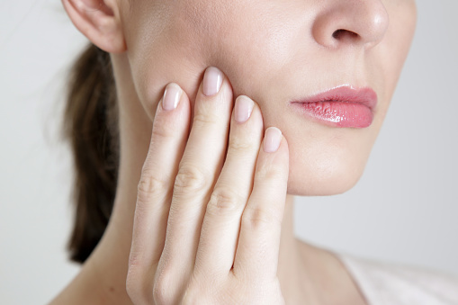 Close up of a woman holding her jaw